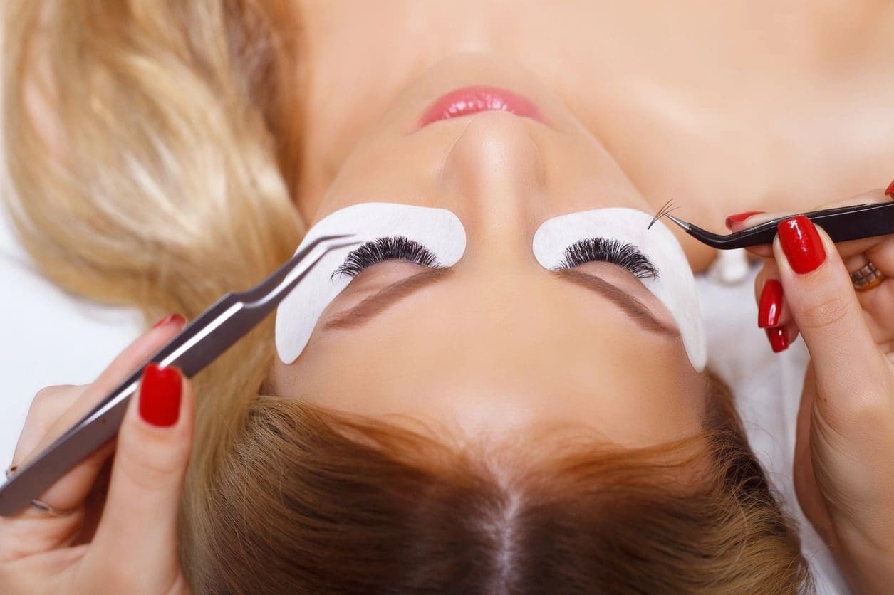 A woman is getting her eyelashes cut off