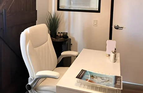 A white desk and chair in front of a window.