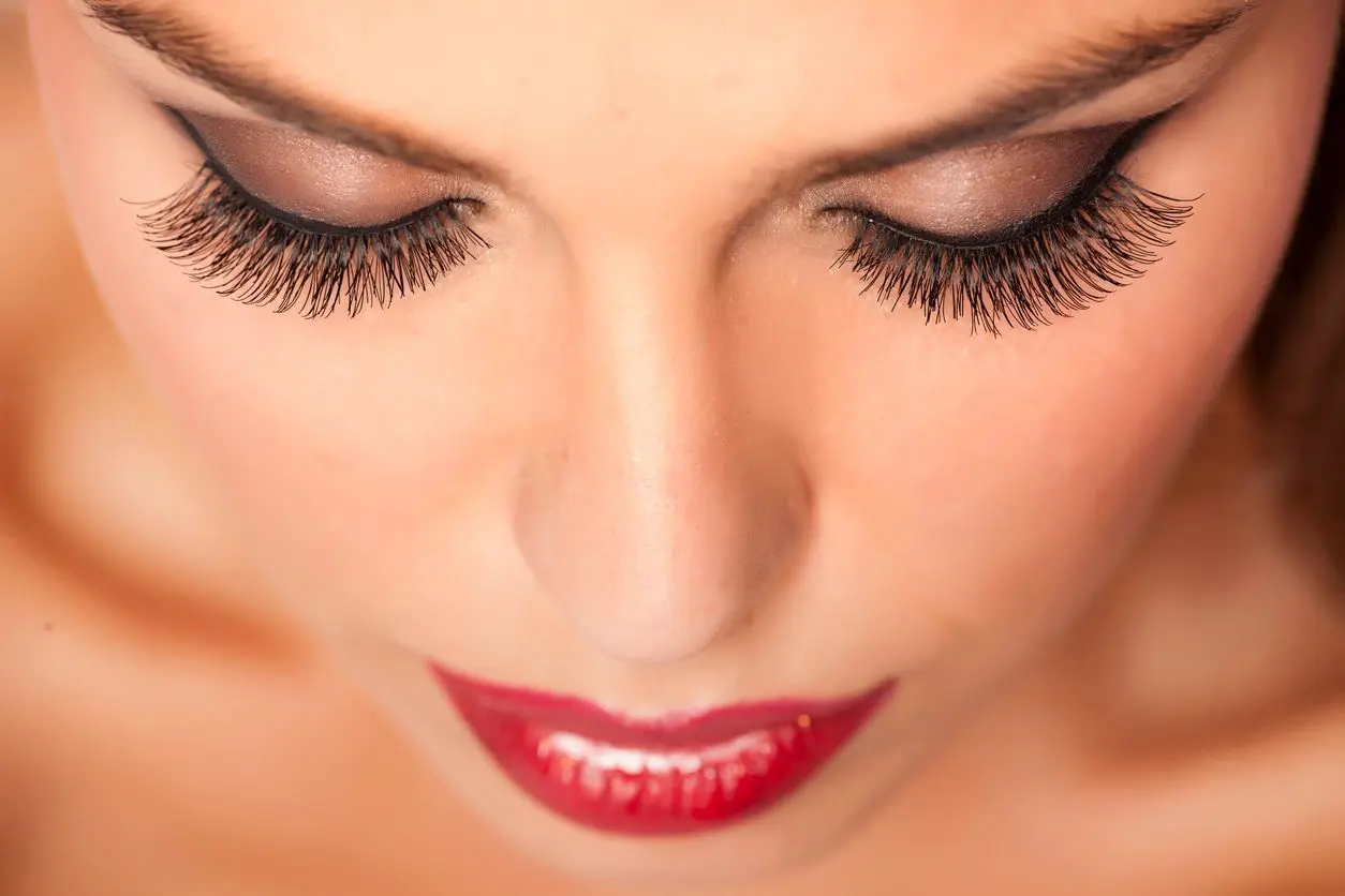 A woman with red lipstick and long lashes.