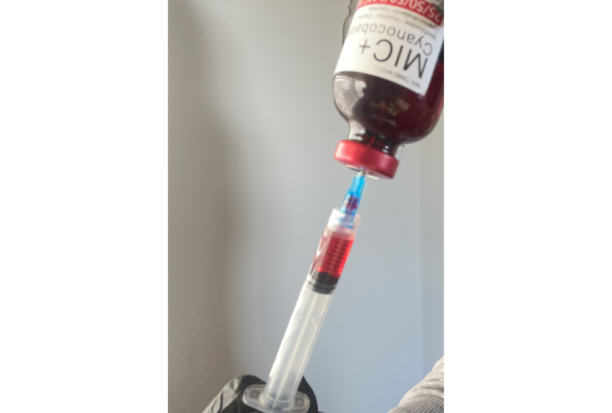 A bottle of wine is being held by a syringe.