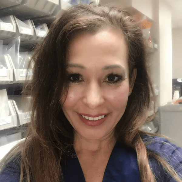 A woman with long hair and blue shirt smiling.